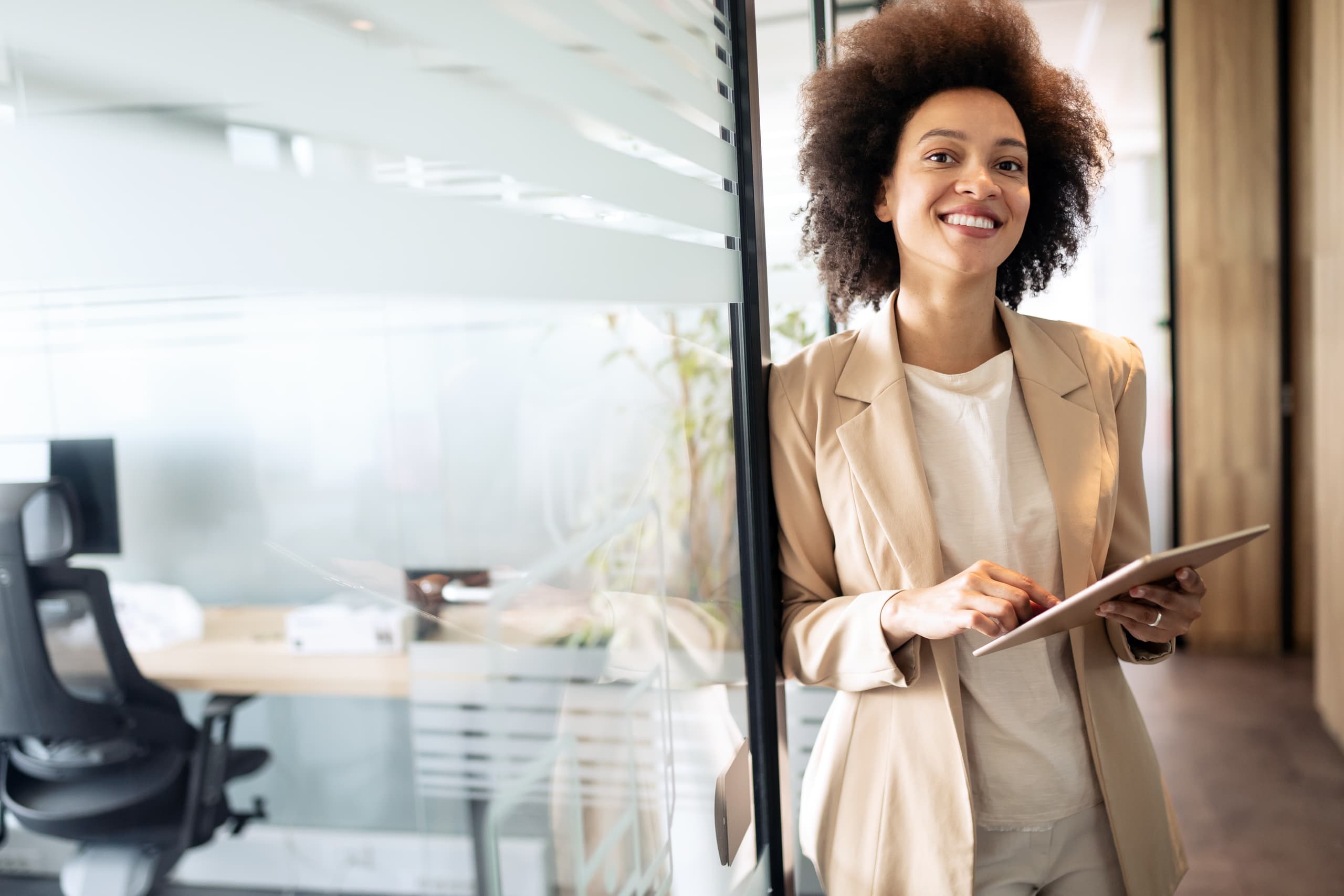 A business woman stands outside her office, smiling at the viewer